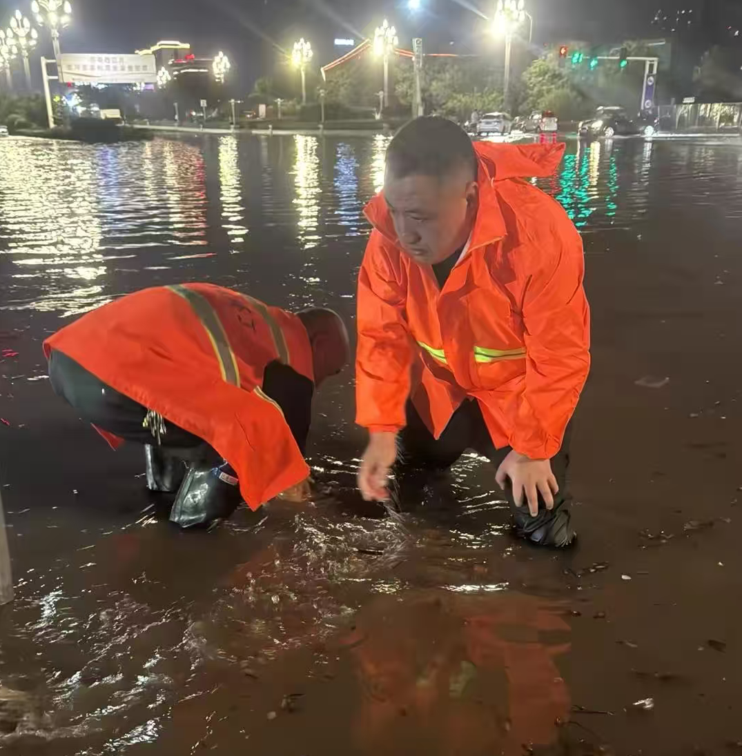 1758494132158.png 神州環境副總經理孔凡超帶領環衛團隊在雨中疏通下水道口.png